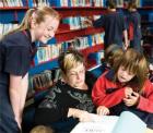 An adult educator reads to a group of children in a library setting