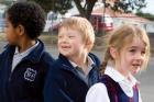 Three primary age children lining up in the playground